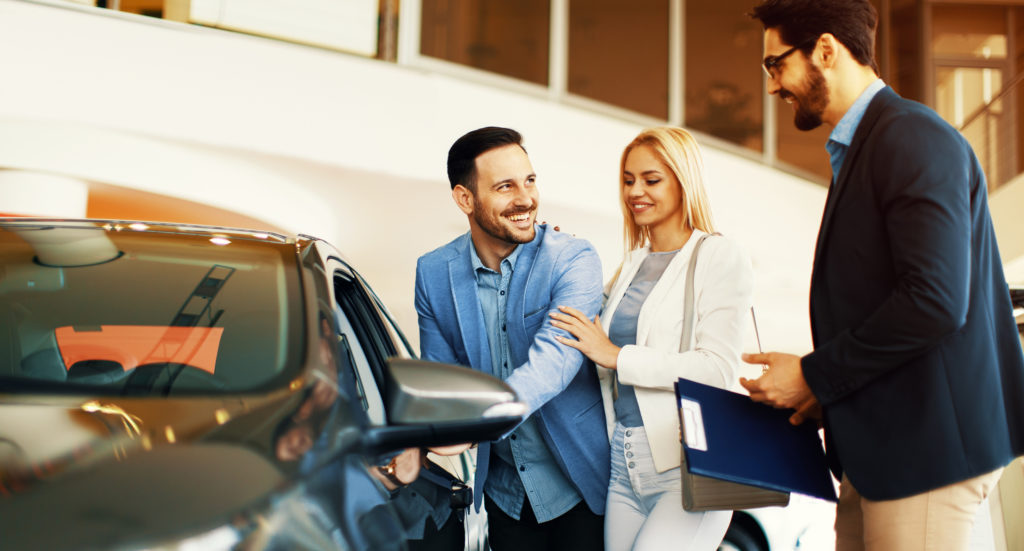 A salesman showing a couple a protentional vehicle 