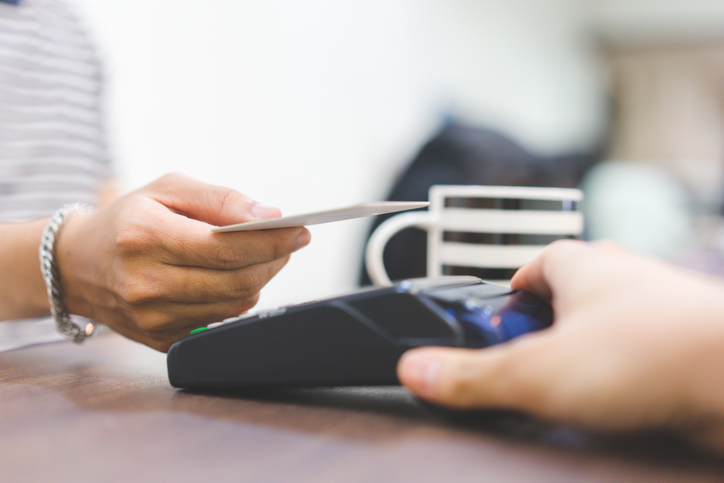 close up customer hand using credit card for paying bill by using payment machine at table in the cafe , contactless payment concept