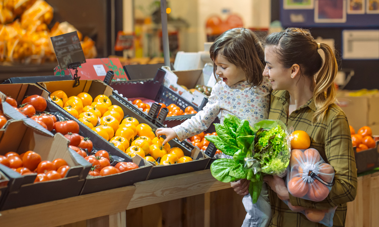  A mom with a young child shopping at a grocery store.