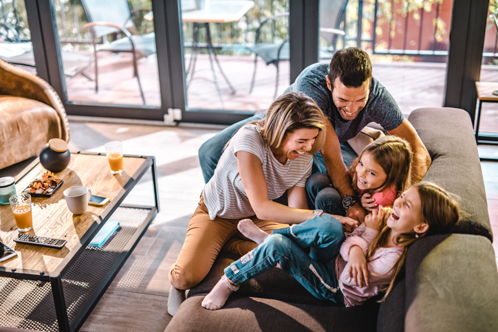 Above view of playful parents tickling their daughters at home.